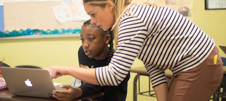 Female teacher helps a student with work on a laptop